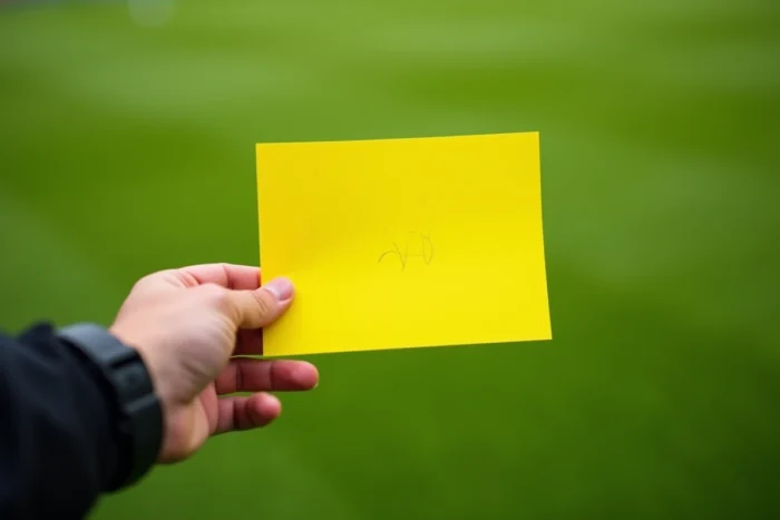 Gros plan sur un carton jaune tenu par un arbitre de football lors d'un match officiel