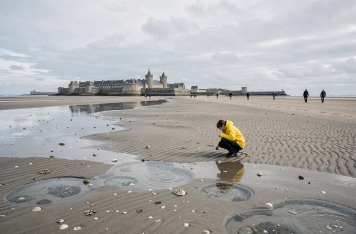 Plage du Sillon à Saint-Malo à marée basse avec la cité corsaire en arrière-plan et promeneurs sur le rivage